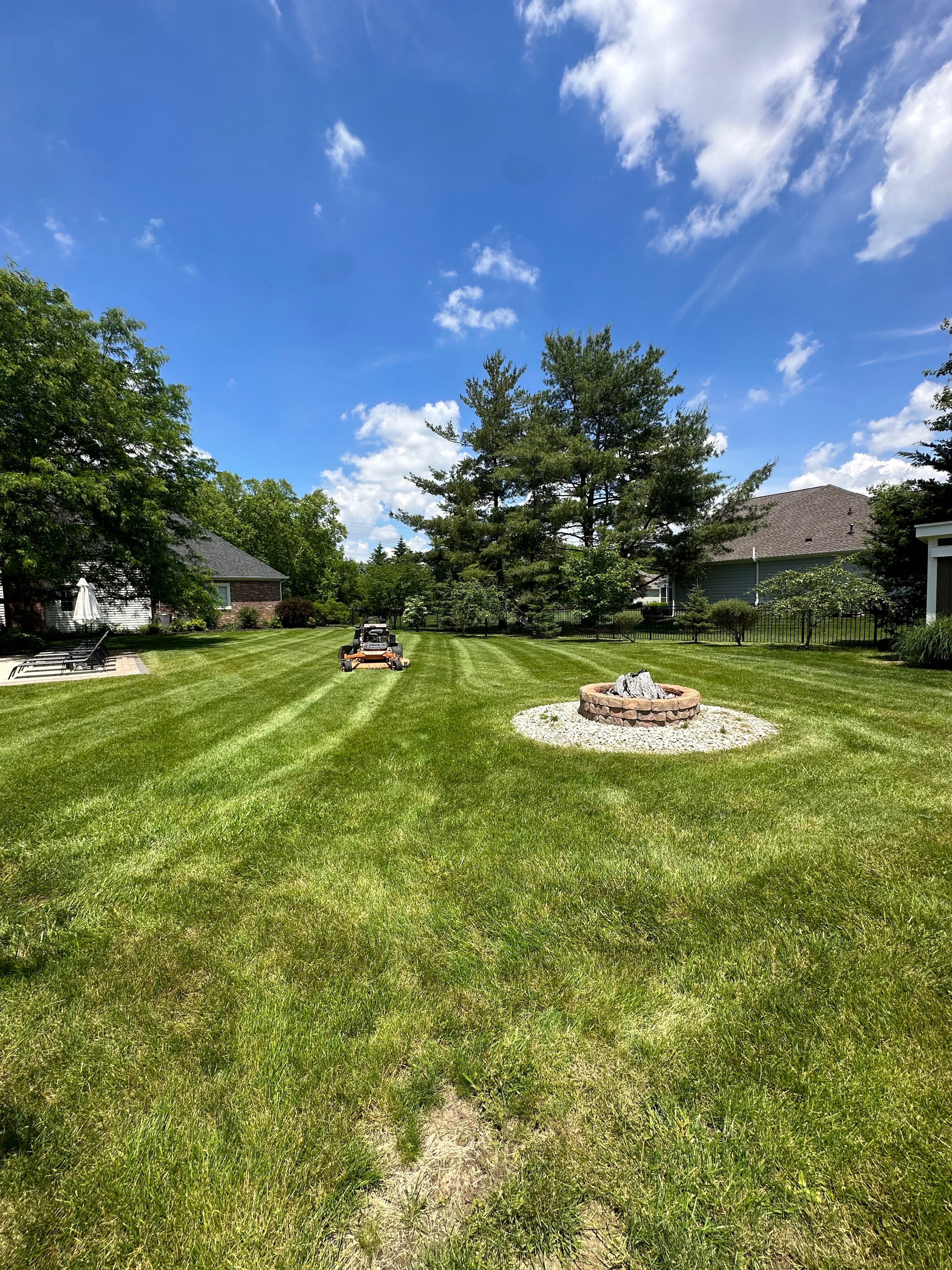 Professional lawn care service with perfect striping and fire pit landscaping by Evergreen
